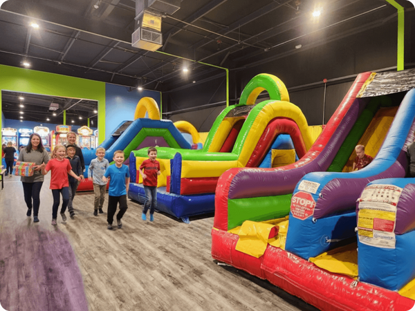 kids get excited as they get to the bounce houses while parents carry birthday presents behind