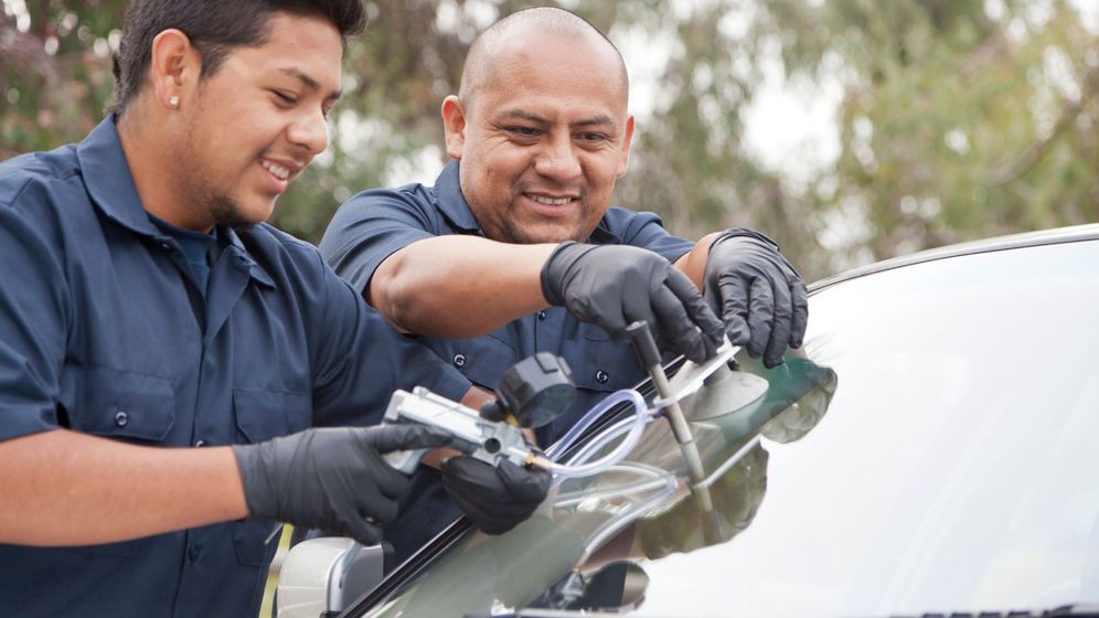 Two auto technicians repair windshield