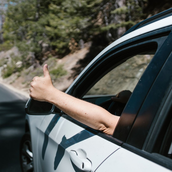 person giving thumbs up out of window