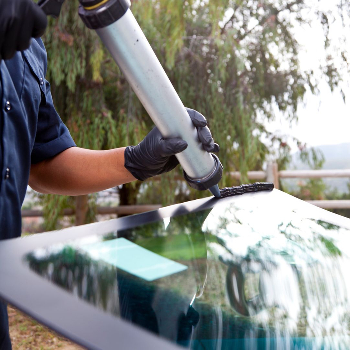 Man applies adhesive to new car windshield