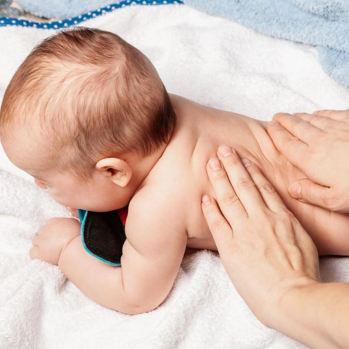 Baby laying on its stomach being adjusted by a chiropractor. 