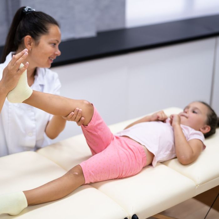 Young girl with her leg being lifted in the air by a chiropractor. 