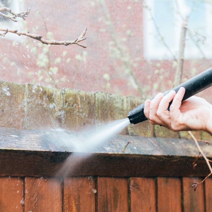 a person power washing a fence