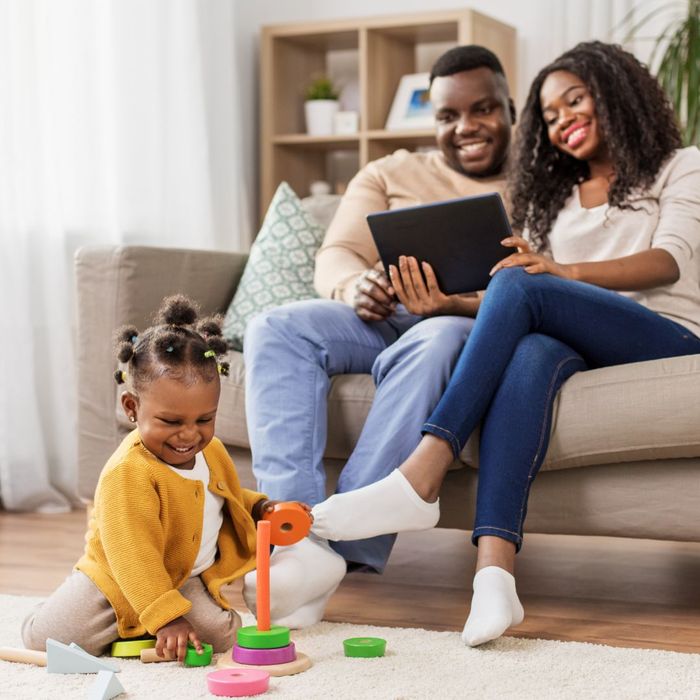 happy parents watching child play in living room