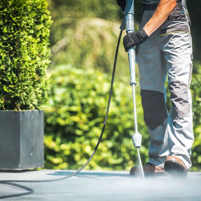 a person pressure washing a cement walkway