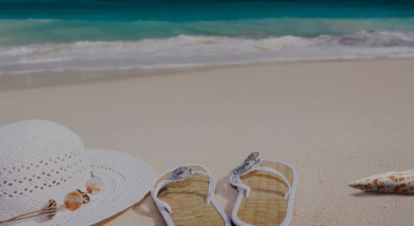 a hat and flipflops on a sandy beach Wyndham Timeshares - Hero.jpg