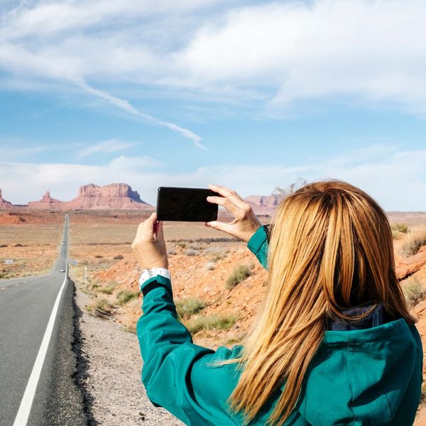 Woman capturing photo of road