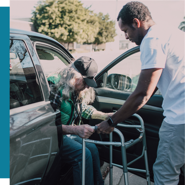 younger man helping older man out of a vehicle
