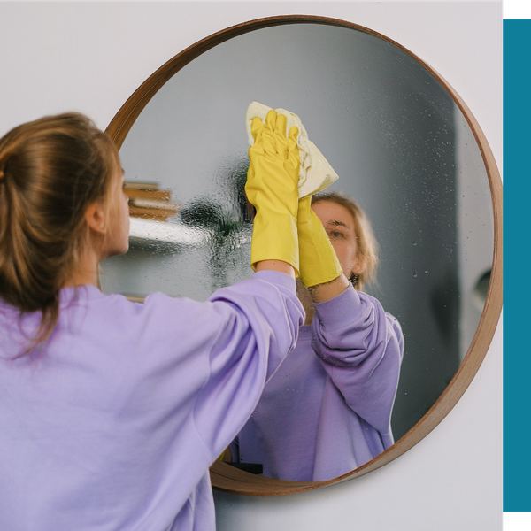 woman wiping circular mirror with rag