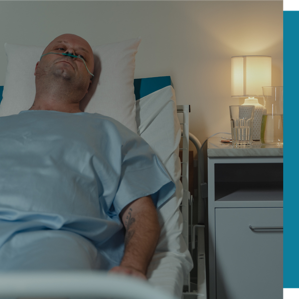 man lying in hospital bed and gown