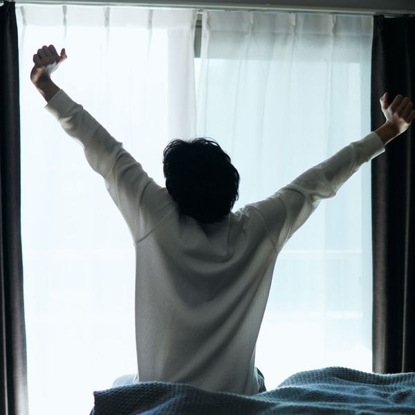 person stretching by a window with light coming in person stretching by a window with light coming in