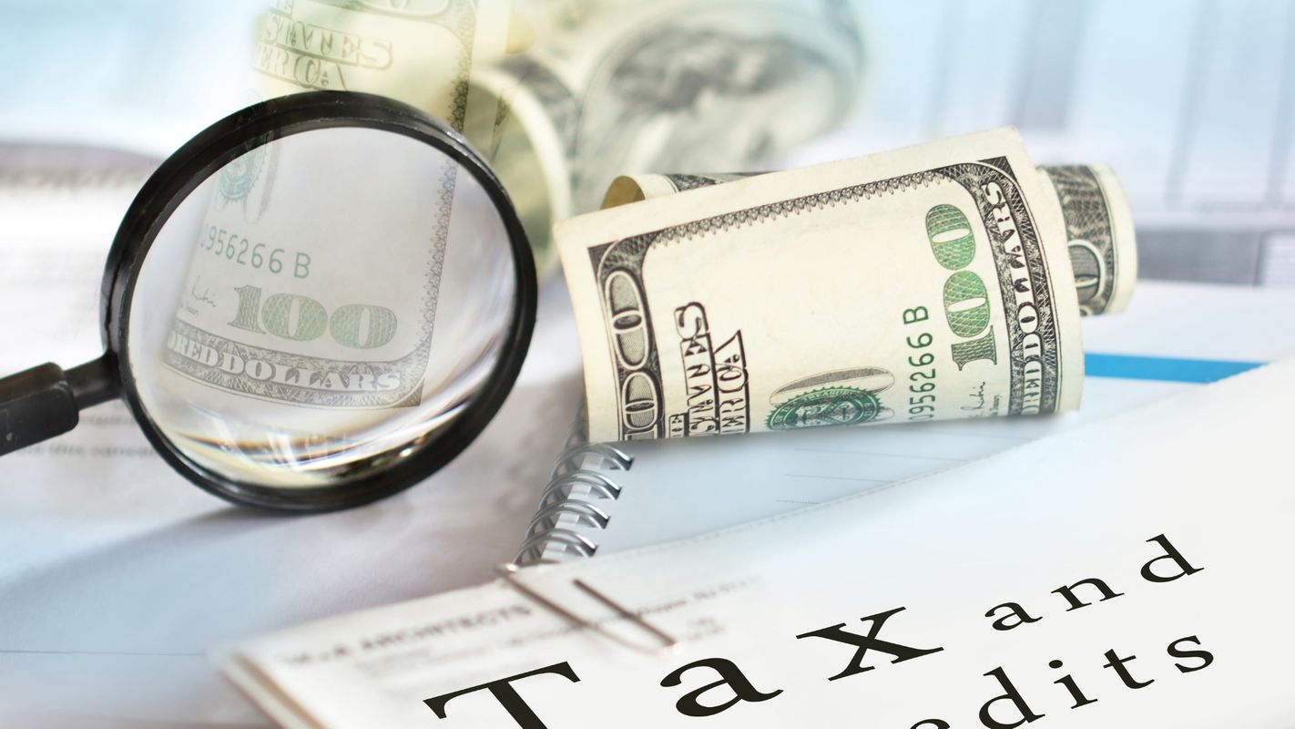 Money, magnifying glass, and tax credit papers