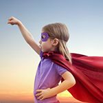 a little girl in a cape and mask in a power pose