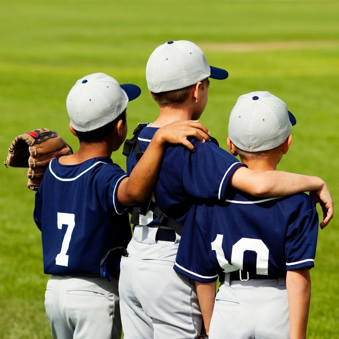 Three young baseball players with their arms around each other. 