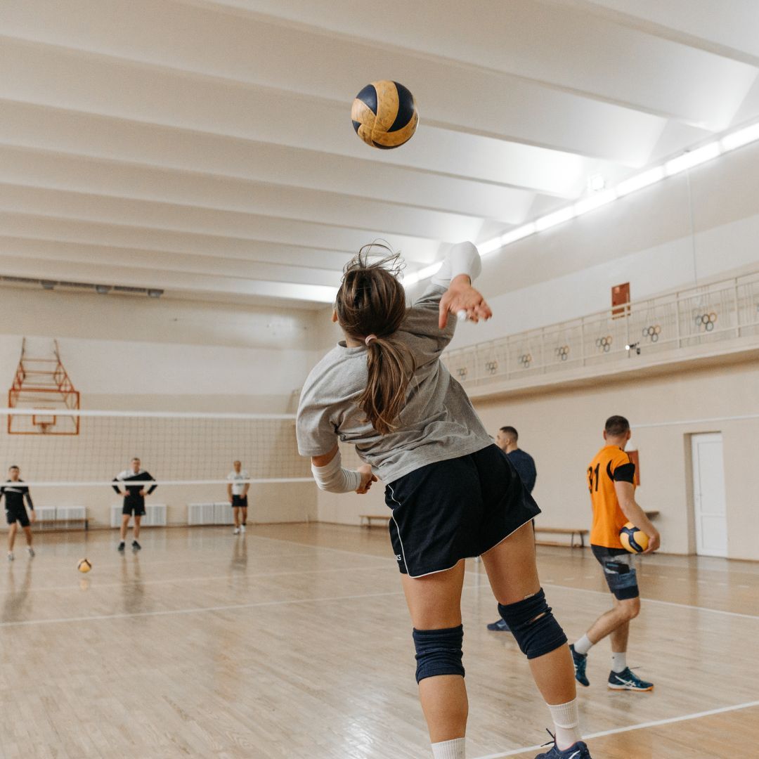 Girl serving volleyball on an indoor court