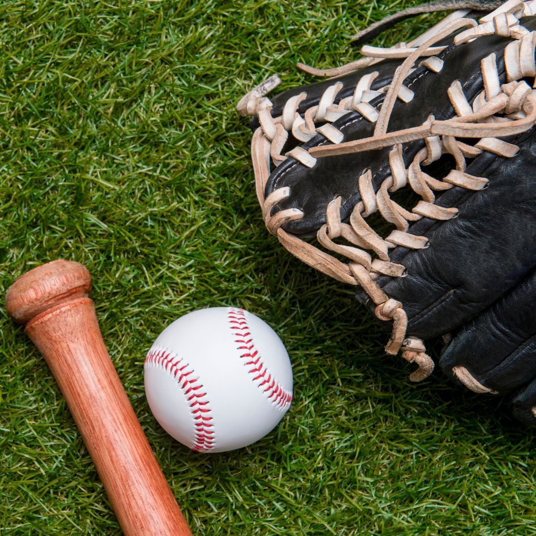 Baseball bat, baseball, and baseball glove on green grass. 