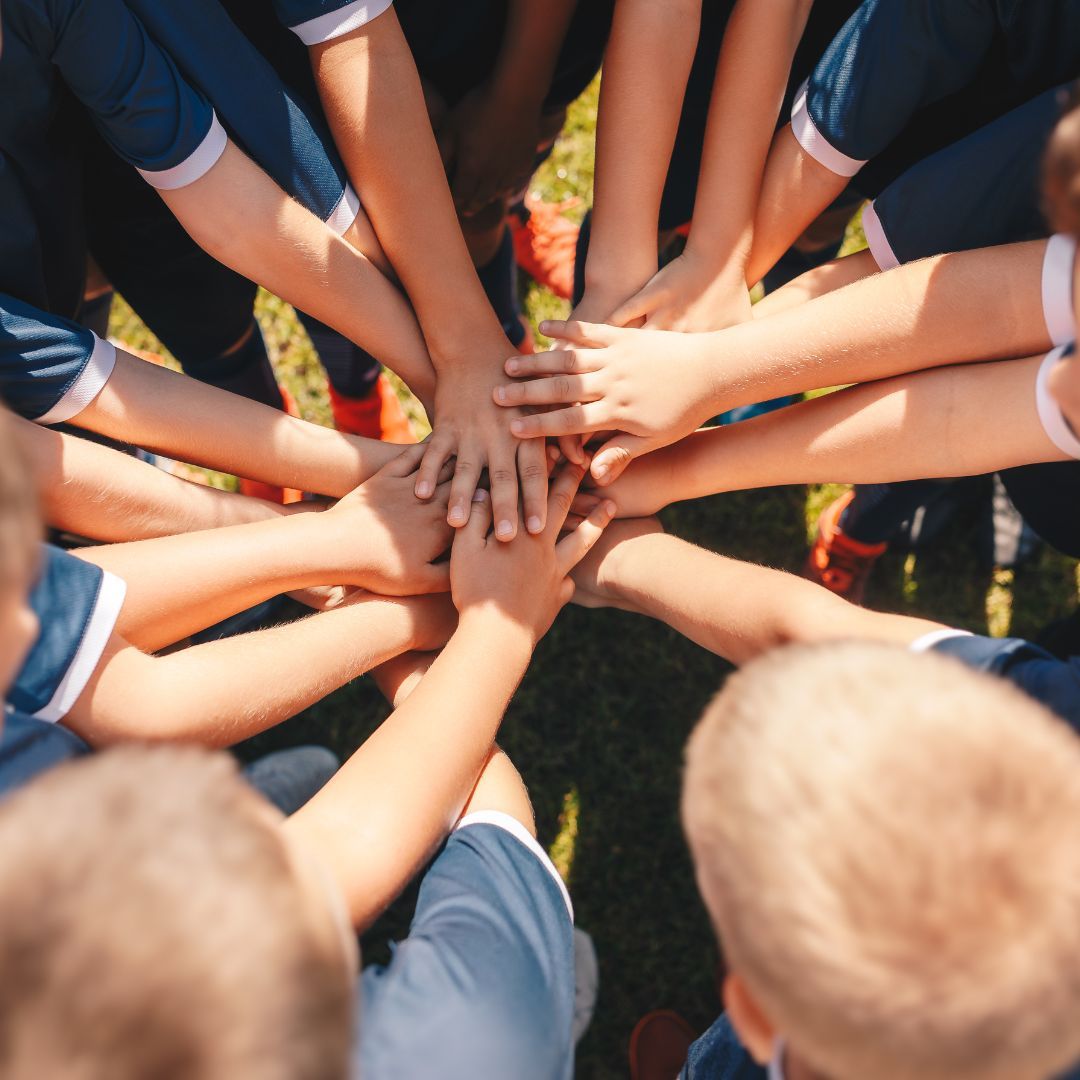 group of young kids stacking their hands in a circle