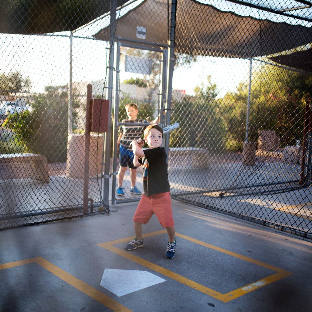 Young boy practicing baseball in a batting cage. 
