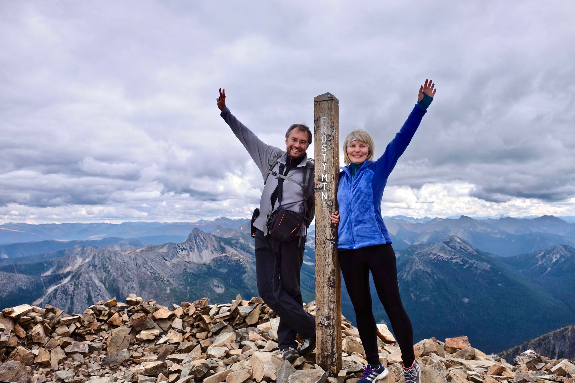 Three diverse hikers celebrating on a mountain summit, raising their arms in victory with a panoramic view of the mountains and sky. Three diverse hikers celebrating on a mountain summit, raising their arms in victory with a panoramic view of the mountains and sky.