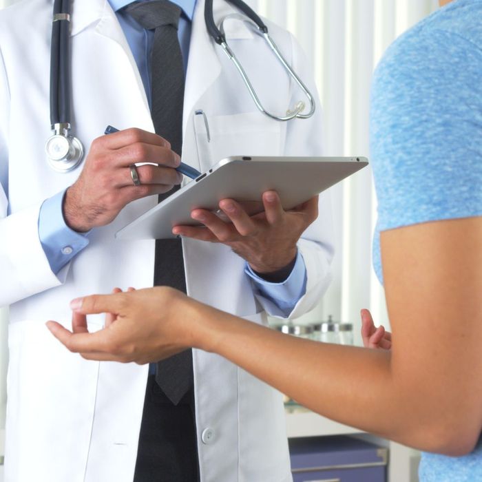 doctor uses tablet while talking with patient