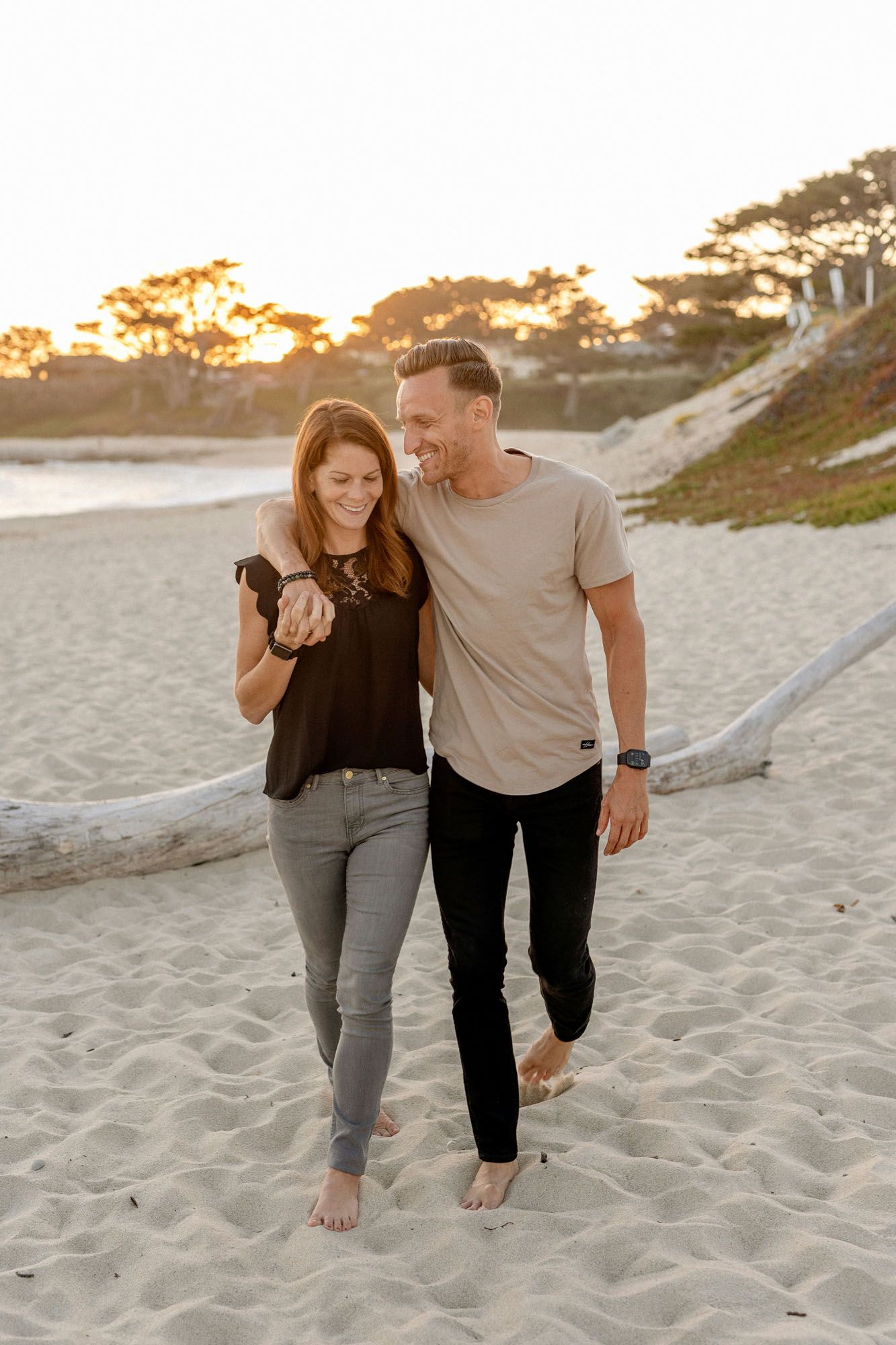A young couple walking arm-in-arm on a sunny beach at sunset with the ocean in the background. A young couple walking arm-in-arm on a sunny beach at sunset with the ocean in the background.