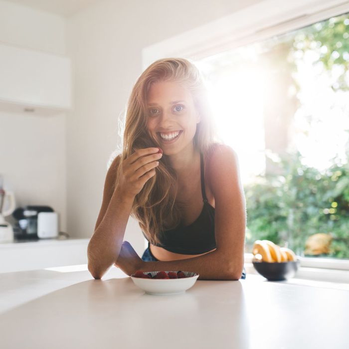 happy woman eating healthy in kitchen