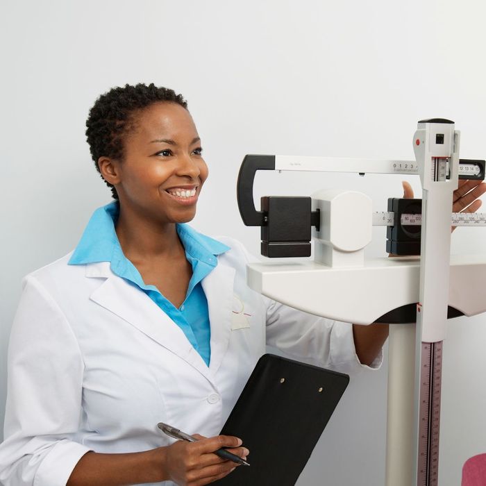 doctor smiling while weighing patient