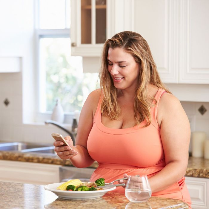 woman looking at phone eating 