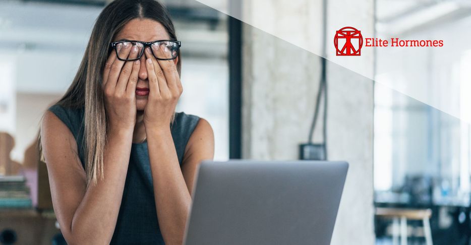 tired woman rubbing eyes while working on laptop