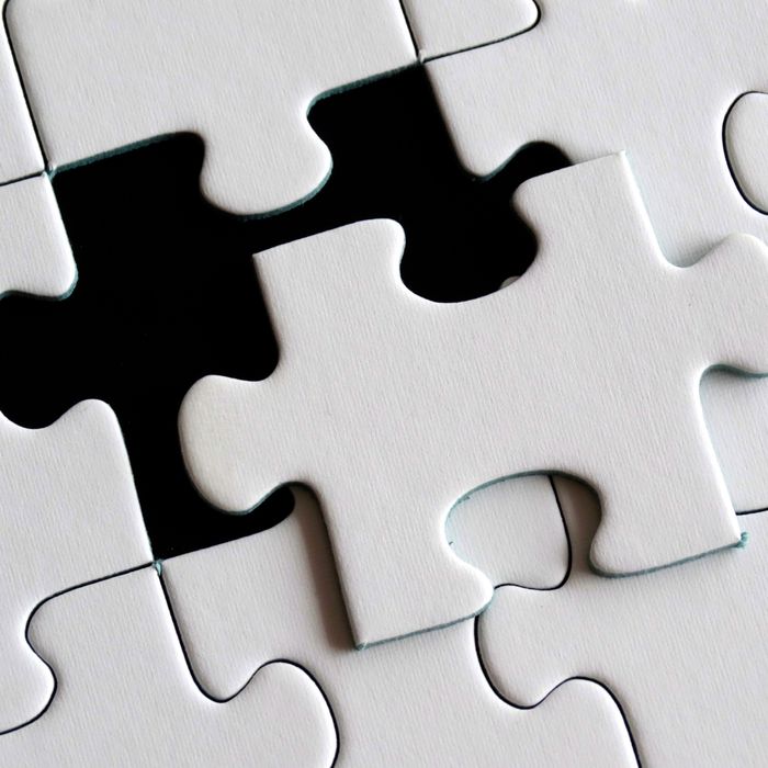 A puzzle piece sitting on top of an incomplete puzzle