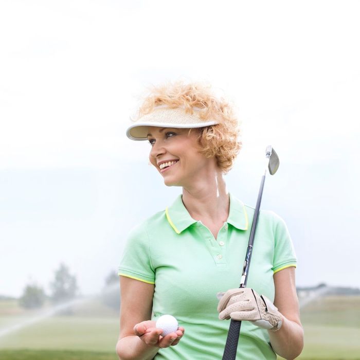 smiling woman holding a golf ball while golfing