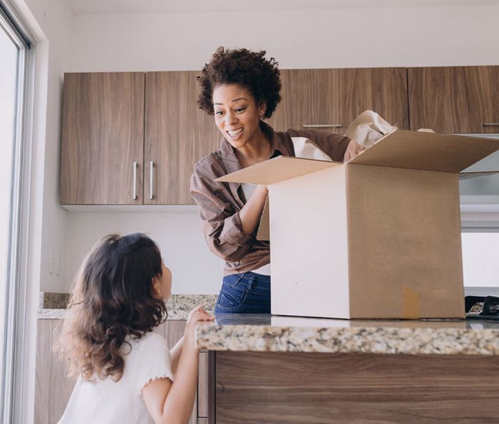 woman packing a box while talking to child