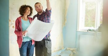 a man and woman looking at bathroom blue prints