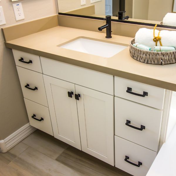 a vanity with white cabinets and tan counter top