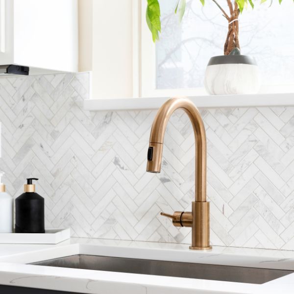 A golden faucet and tile backsplash