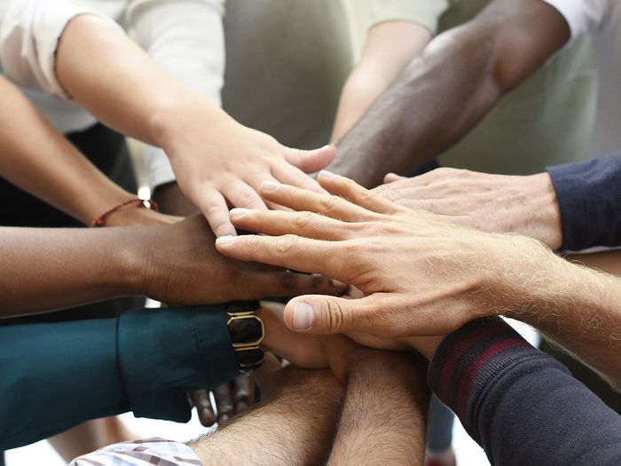 An image of a bunch of people putting their hands into the center of a circle.