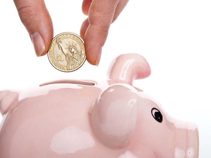 An image of a coin being dropped into a piggy bank.