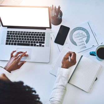 woman on laptop taking notes with right hand