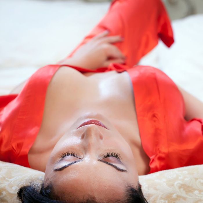 Woman wearing a red robe posing while laying down. 