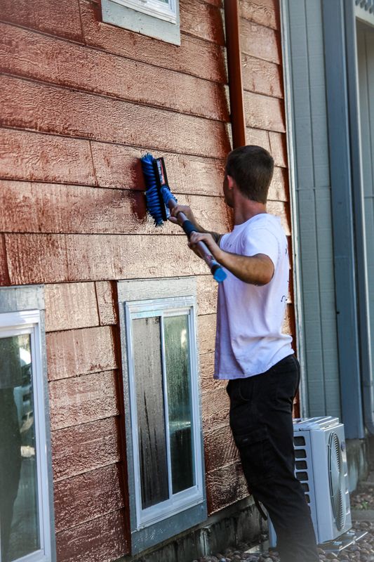 scrubbing house siding with broom