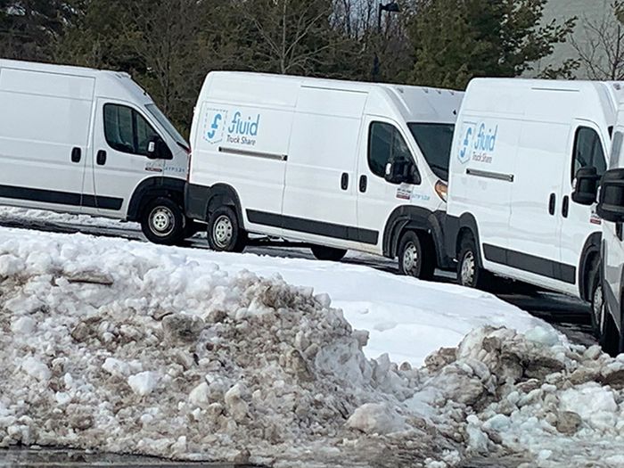 A line of commercial fleet vans driving down the road