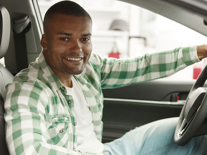 smiling man sitting in his new car