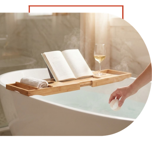 A serene, spa-like bathroom remodel featuring a freestanding soaking tub with a bath tray, book, and wine