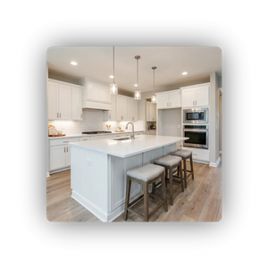 A bright, modern kitchen remodel with white shaker cabinets, a large central island with seating, pendant lights, and stainless steel appliances