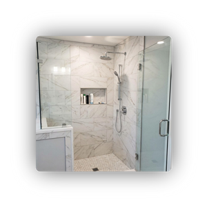 a custom shower remodel featuring large-format marble-look tiles, a built-in niche, a rainfall showerhead, and a frameless glass enclosure