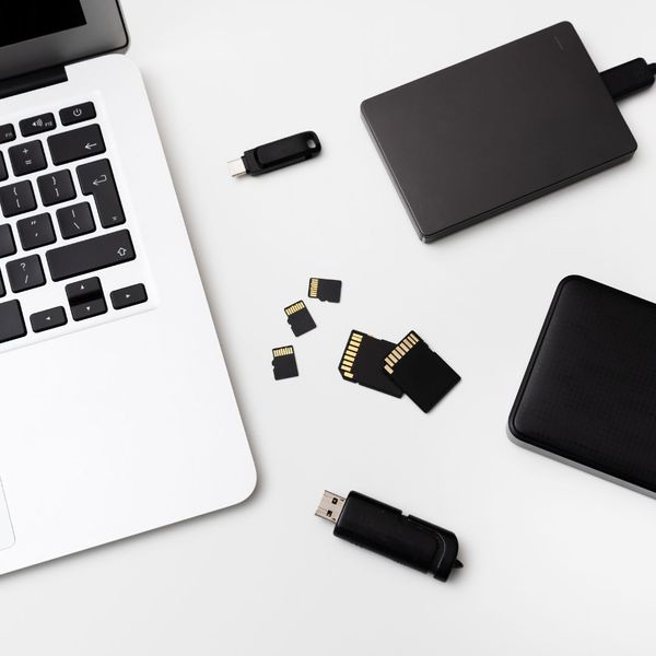 laptop sitting next to USBs and other digital storage devices