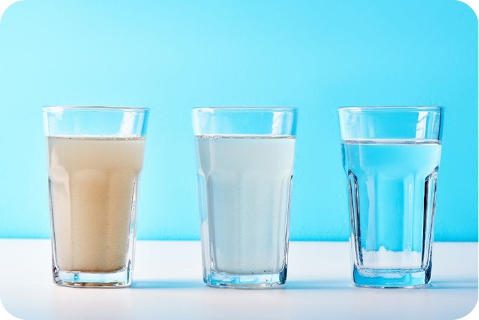 Three glasses of water, two with contaminants, one with clean, fresh water. 