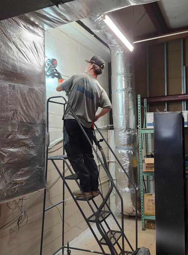 Image of a worker in the basement working with a tool on a step ladder Image of a worker in the basement working with a tool on a step ladder