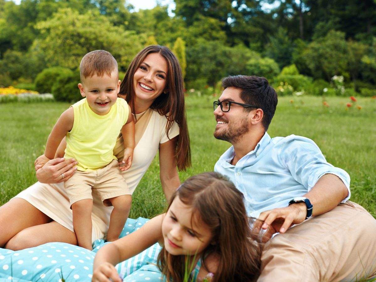 happy young family sitting in grass happy young family sitting in grass