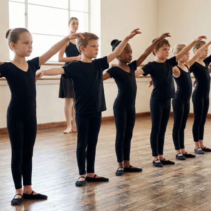 children in a dance class stand in a straight line, all performing the same arm movement